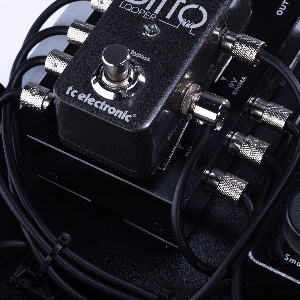 Compact solderless DC plugs and custom power leads beside a guitar looper pedal